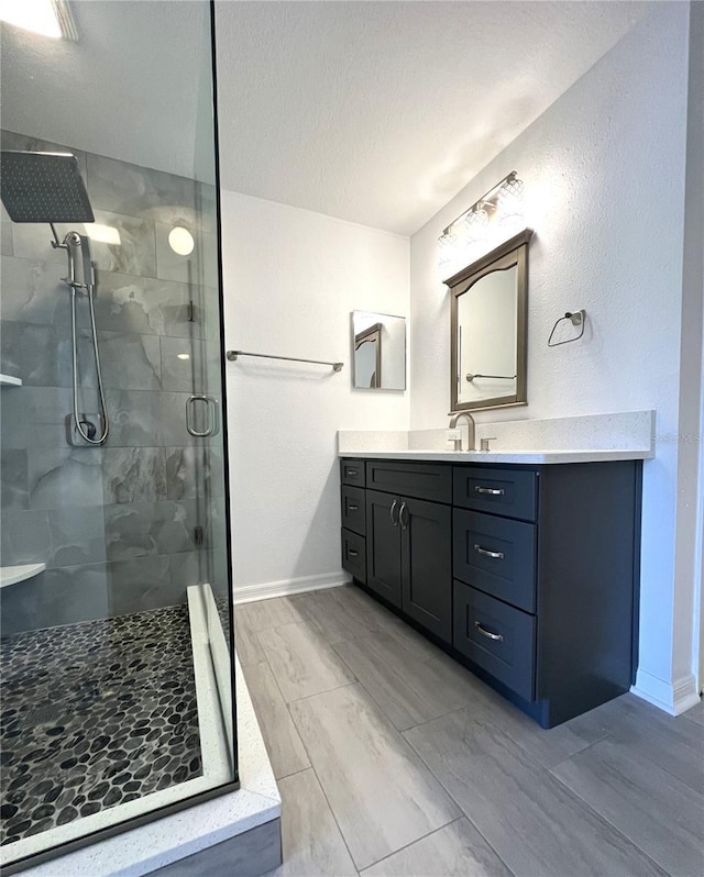 bathroom with a shower stall, vanity, and baseboards