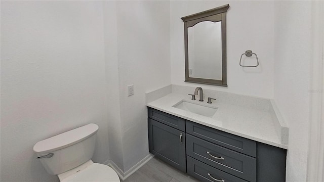 bathroom with baseboards, toilet, and vanity
