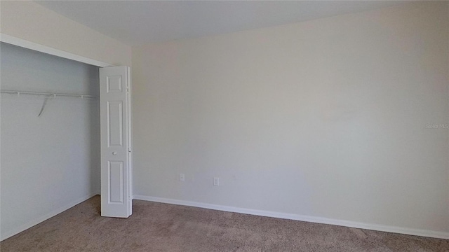 unfurnished bedroom featuring baseboards, carpet flooring, and a closet
