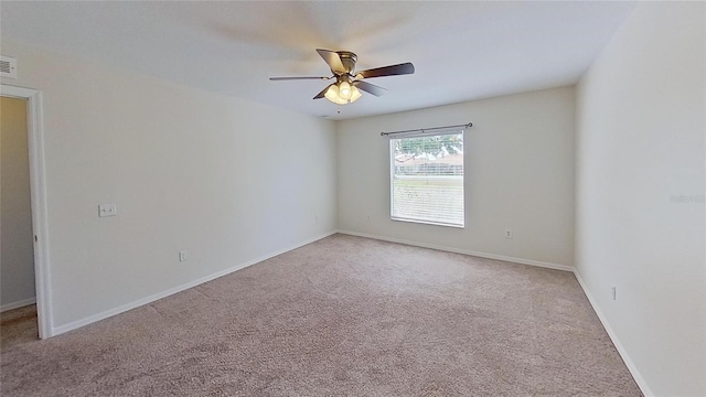 empty room featuring baseboards, a ceiling fan, and light carpet