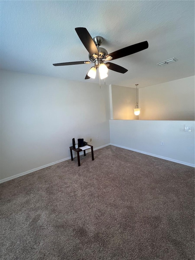 empty room with ceiling fan, visible vents, baseboards, a textured ceiling, and carpet floors