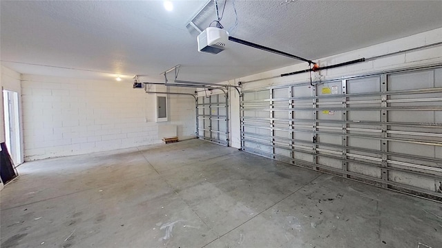 garage with a garage door opener, concrete block wall, and electric panel
