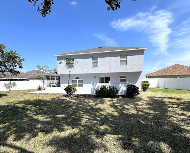 rear view of house featuring a sunroom, stucco siding, and a fenced backyard