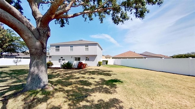 rear view of property featuring stucco siding, a lawn, and a fenced backyard