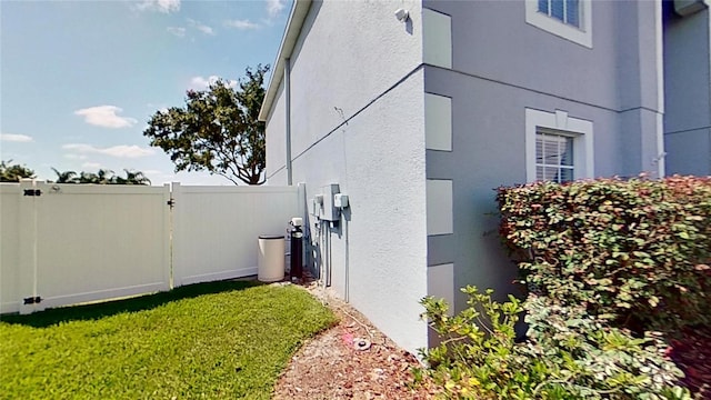 view of property exterior with stucco siding, fence, and a gate