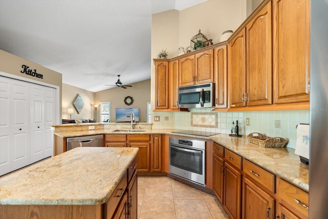 kitchen featuring ceiling fan, appliances with stainless steel finishes, light stone counters, a sink, and backsplash