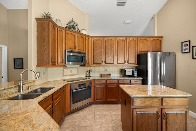 kitchen with backsplash, visible vents, a sink, light stone counters, and stainless steel appliances