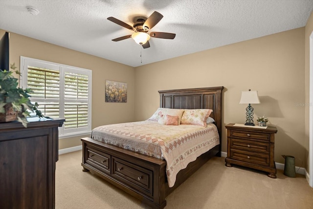 bedroom featuring a textured ceiling, baseboards, light carpet, and ceiling fan