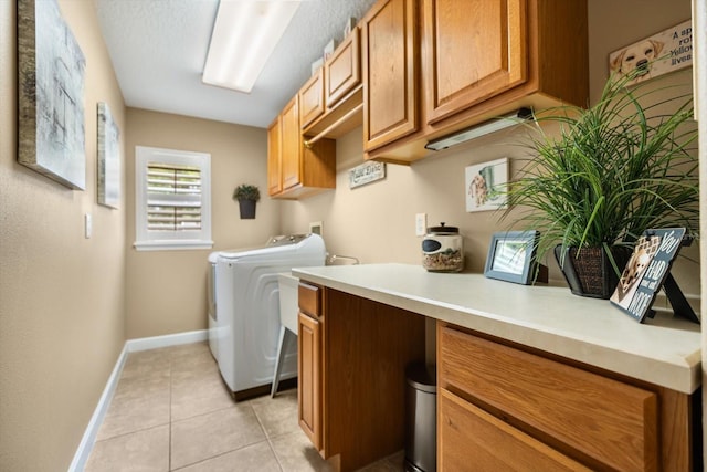 washroom featuring cabinet space, independent washer and dryer, baseboards, and light tile patterned floors