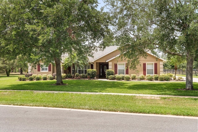view of front of house with stucco siding, fence, and a front yard