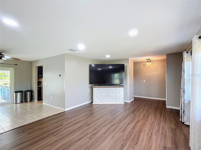 unfurnished living room with baseboards, a ceiling fan, wood finished floors, and visible vents