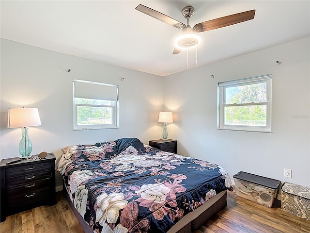 bedroom with a ceiling fan, wood finished floors, and multiple windows
