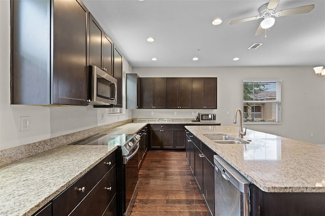 kitchen featuring dark brown cabinets, appliances with stainless steel finishes, a sink, recessed lighting, and dark wood-type flooring