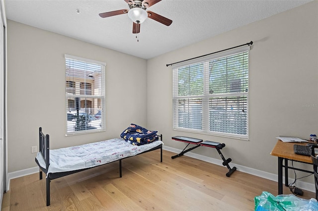 sitting room with baseboards, a textured ceiling, light wood-style flooring, and ceiling fan