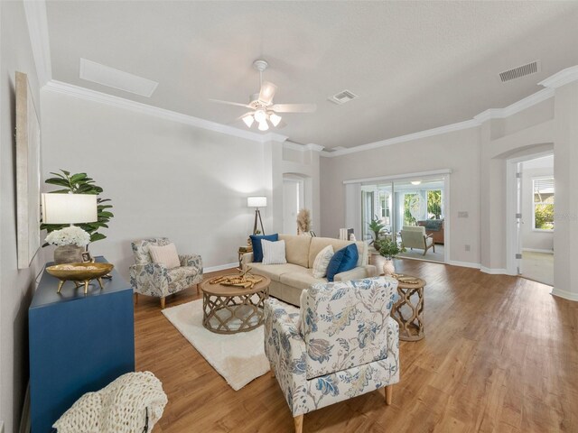 951 Chapman Loop, The Villages, FL 32162 - living room featuring arched walkways, ornamental molding, light wood-style floors, baseboards, and a ceiling fan