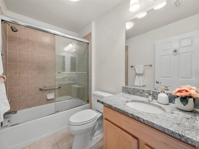 951 Chapman Loop, The Villages, FL 32162 - full bathroom featuring tile patterned floors, vanity, shower / bath combination with glass door, toilet, and a textured ceiling
