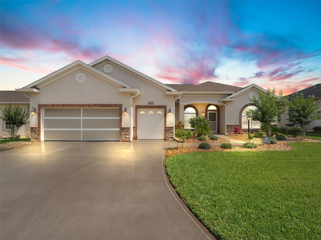 ranch-style house with an attached garage, stone siding, stucco siding, a lawn, and concrete driveway