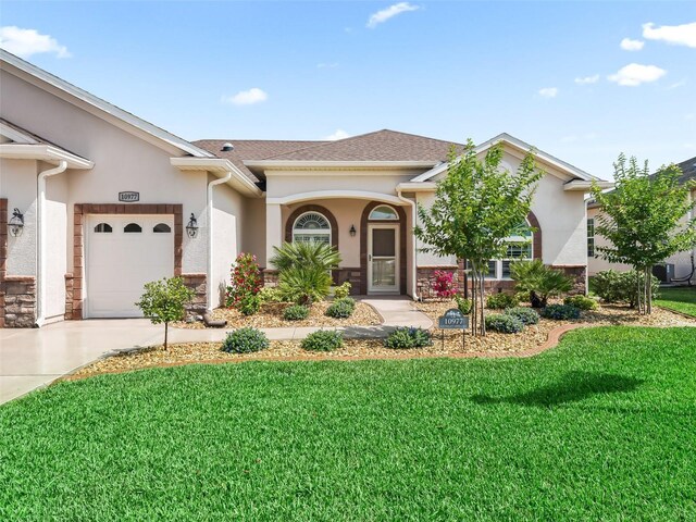 view of front of property with an attached garage, stone siding, stucco siding, a front yard, and driveway