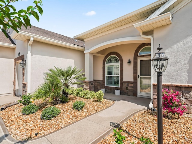 doorway to property featuring stone siding, stucco siding, roof with shingles, and a porch