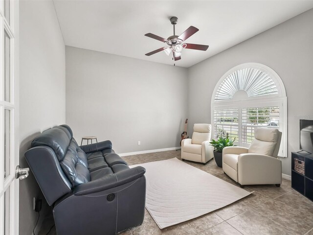 living area featuring tile patterned floors, baseboards, and ceiling fan