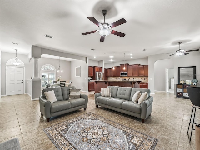 living room with light tile patterned floors, arched walkways, a ceiling fan, and visible vents