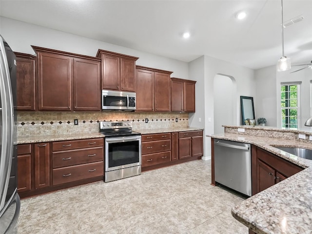 kitchen featuring a sink, stainless steel appliances, tasteful backsplash, visible vents, and arched walkways