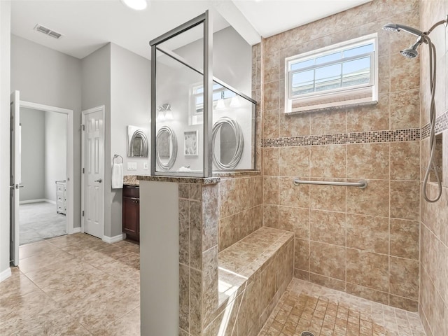 full bath with tiled shower, tile patterned floors, vanity, and visible vents