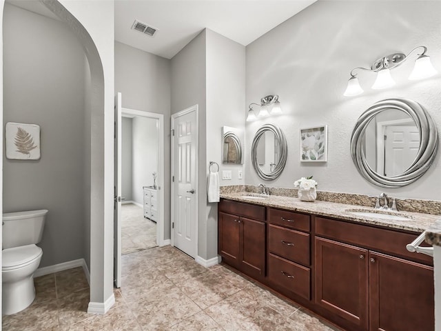 bathroom featuring a sink, double vanity, toilet, and visible vents