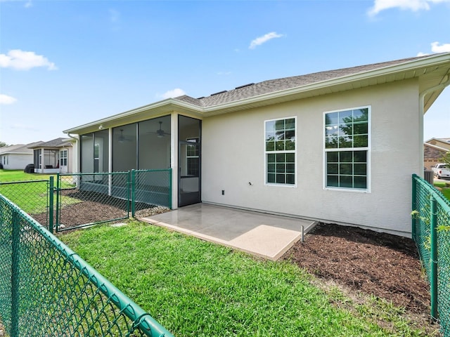 back of property featuring a ceiling fan, a sunroom, stucco siding, a lawn, and a fenced backyard