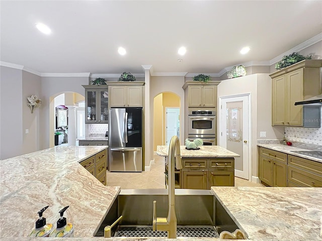 1473 Lakemist Ln, Clermont, FL 34711 - kitchen featuring a sink, arched walkways, tasteful backsplash, and appliances with stainless steel finishes