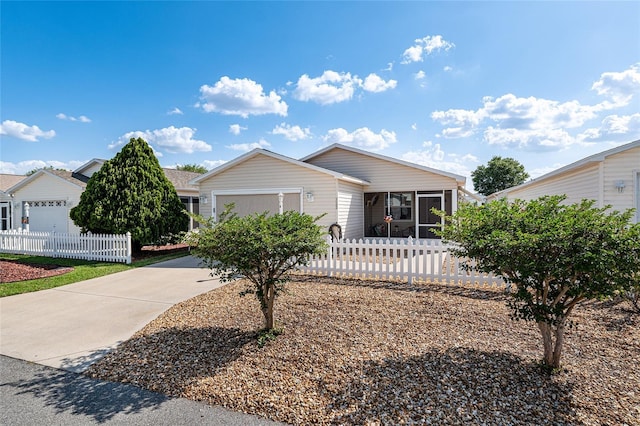 ranch-style home featuring driveway, a sunroom, an attached garage, and fence private yard