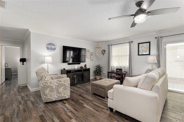 living room with a textured ceiling, dark wood-style flooring, ceiling fan, visible vents, and crown molding