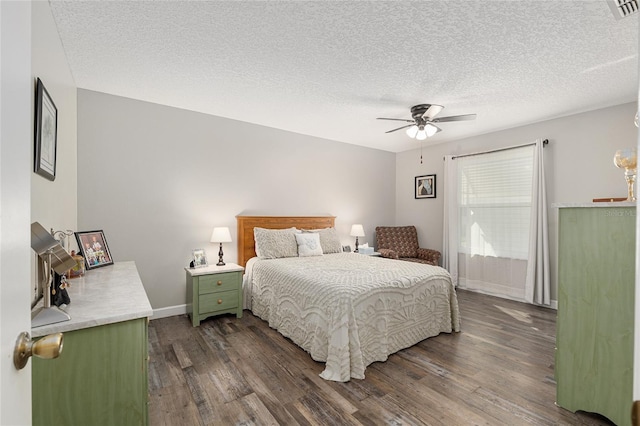 bedroom featuring a textured ceiling, visible vents, ceiling fan, dark wood-style floors, and baseboards