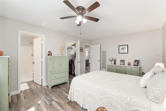 bedroom featuring a closet, wood finished floors, visible vents, a spacious closet, and connected bathroom