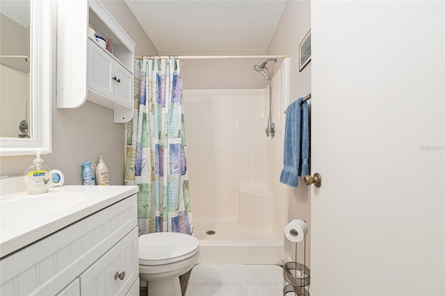 full bathroom with vanity, toilet, a stall shower, and a textured ceiling