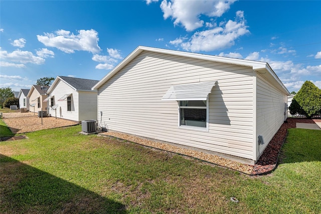 view of side of home featuring a yard and central AC