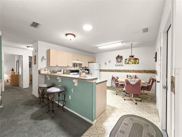 2102 Estevez Dr, Lady Lake, FL 32159 - kitchen featuring freestanding refrigerator, light brown cabinets, a peninsula, a breakfast bar, and under cabinet range hood