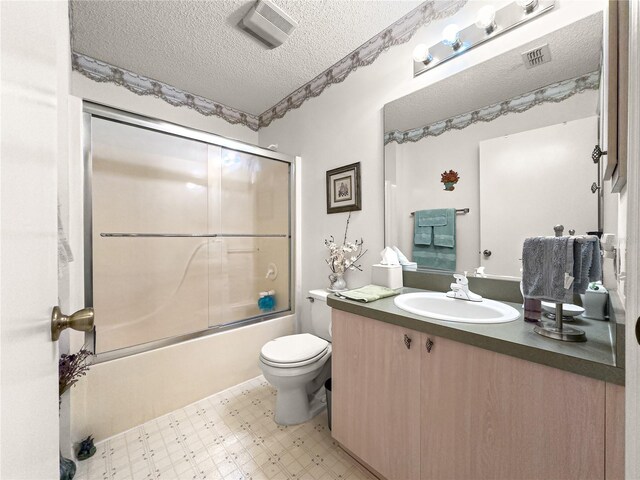 2102 Estevez Dr, Lady Lake, FL 32159 - bathroom featuring tile patterned floors, vanity, bath / shower combo with glass door, toilet, and a textured ceiling