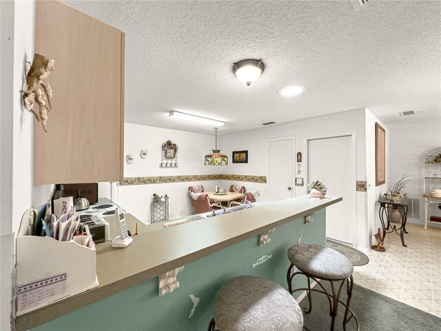 2102 Estevez Dr, Lady Lake, FL 32159 - kitchen with a breakfast bar, a textured ceiling, and a peninsula