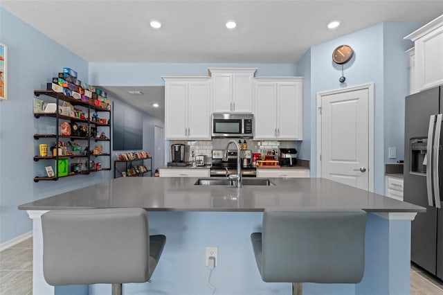 5354 Travertine St, Mount Dora, FL 32757 - kitchen featuring appliances with stainless steel finishes, decorative backsplash, a sink, and a kitchen bar