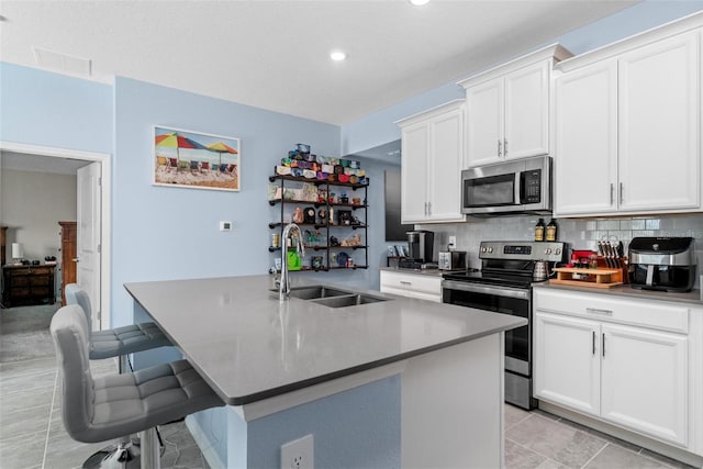 5354 Travertine St, Mount Dora, FL 32757 - kitchen with appliances with stainless steel finishes, tasteful backsplash, a sink, white cabinets, and an island with sink