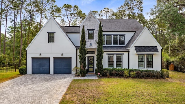 modern farmhouse style home with stucco siding, decorative driveway, a shingled roof, and a front lawn
