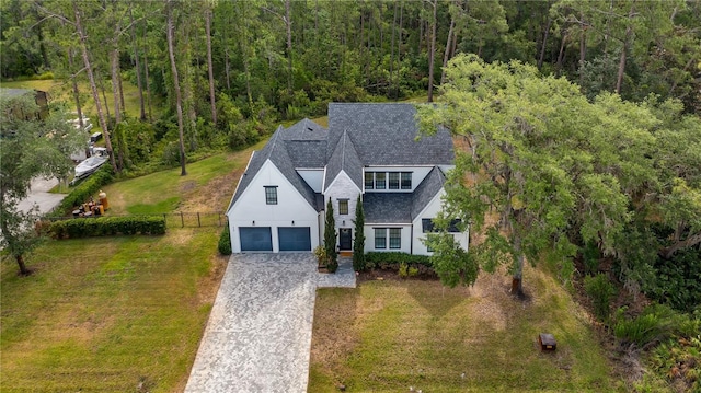 view of front facade with driveway, a view of trees, fence, a front lawn, and a shingled roof