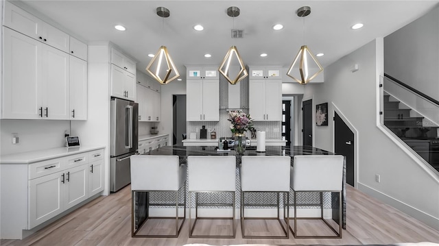 kitchen featuring white cabinets, a kitchen breakfast bar, visible vents, and high end refrigerator