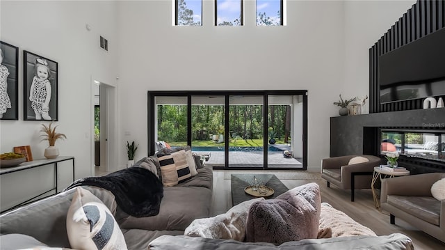 living room featuring a high ceiling, wood finished floors, and visible vents