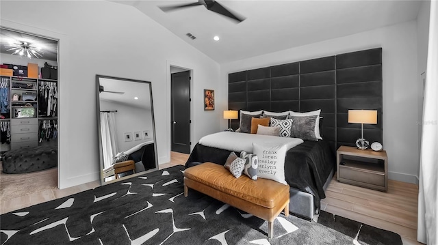 bedroom featuring visible vents, a walk in closet, wood finished floors, and vaulted ceiling