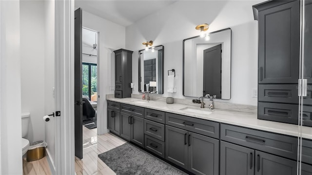 bathroom featuring connected bathroom, double vanity, toilet, and a sink