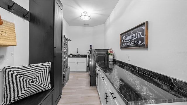 kitchen with dark stone counters, white cabinets, separate washer and dryer, and visible vents