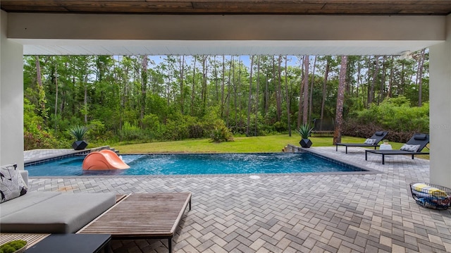 outdoor pool with a water slide, a yard, and a patio area