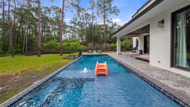 outdoor pool featuring a patio, ceiling fan, and a lawn